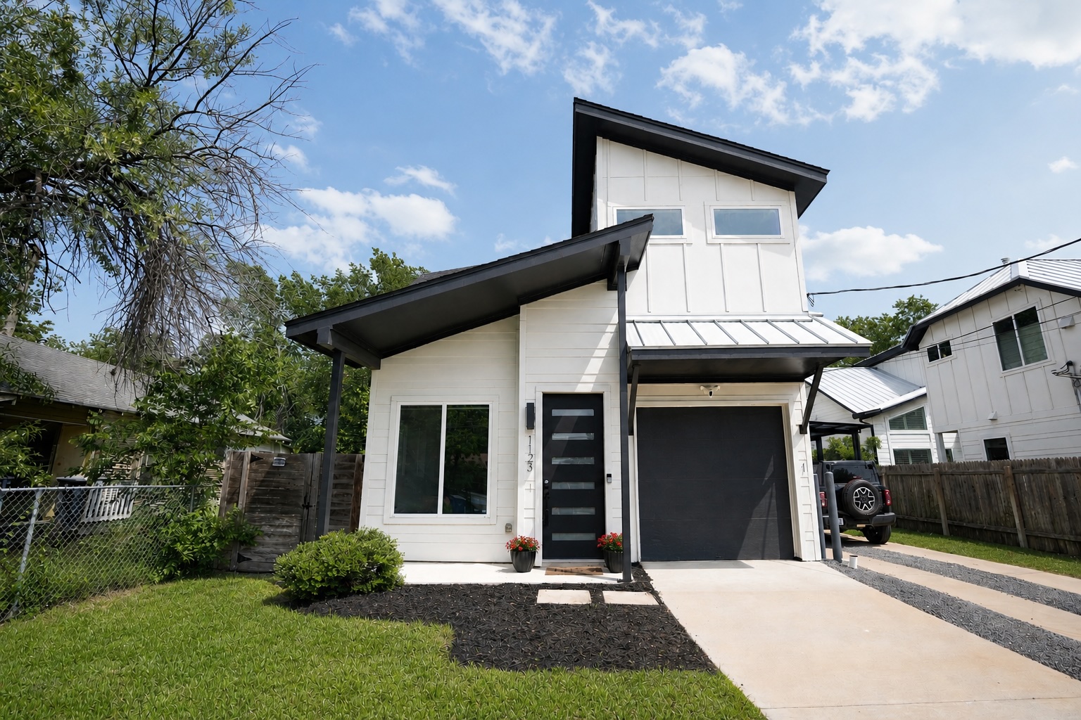1123 Omega Avenue, Unit 1 Austin, TX 78721 - Photo 1 of 40 Contemporary architectural design featuring white vertical siding, a dark metal roof, and an attached single-car garage