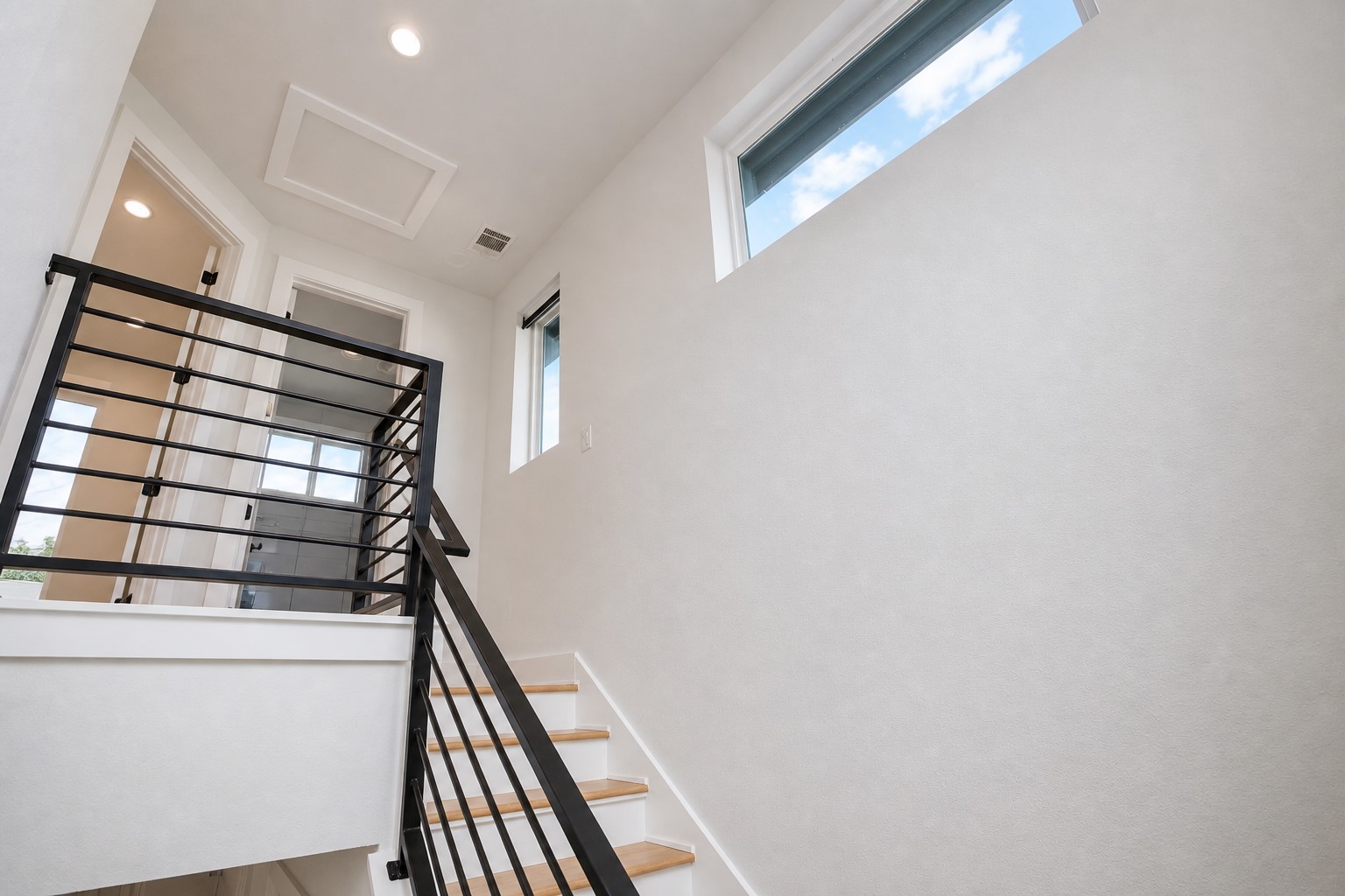 1123 Omega Avenue, Unit 1 Austin, TX 78721 - Photo 13 of 40 Staircase featuring light wood-finish treads and risers with a contemporary black metal railing