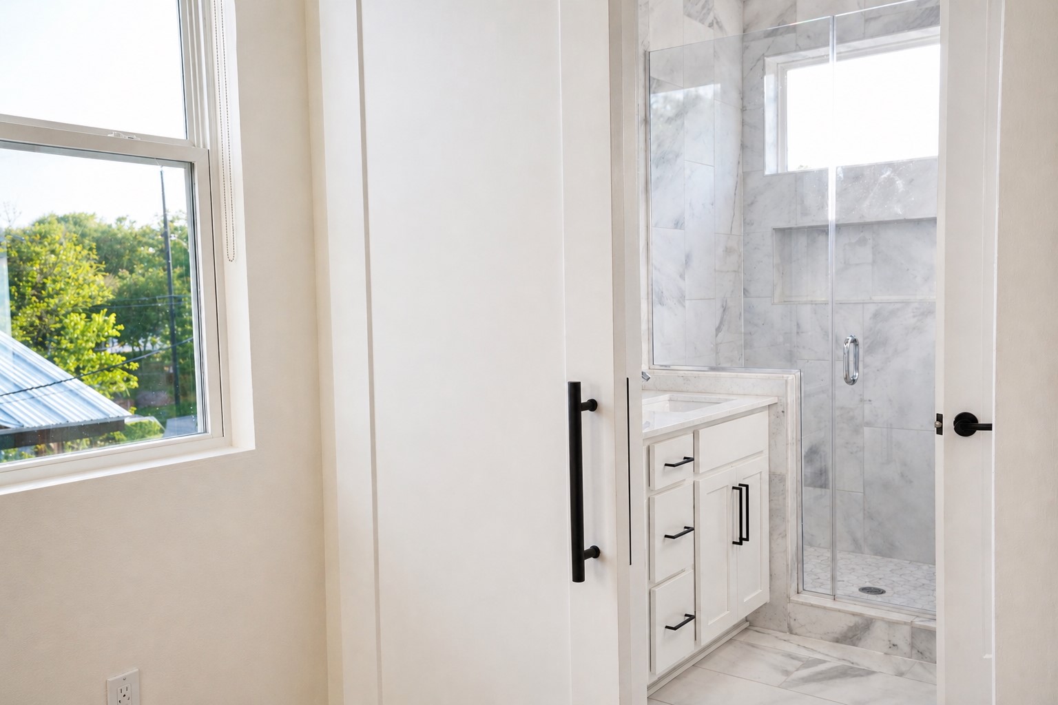 1123 Omega Avenue, Unit 1 Austin, TX 78721 - Photo 17 of 40 Contemporary bathroom featuring a glass-enclosed shower with marble-look tile, a built-in shower niche, and a white vanity with black hardware