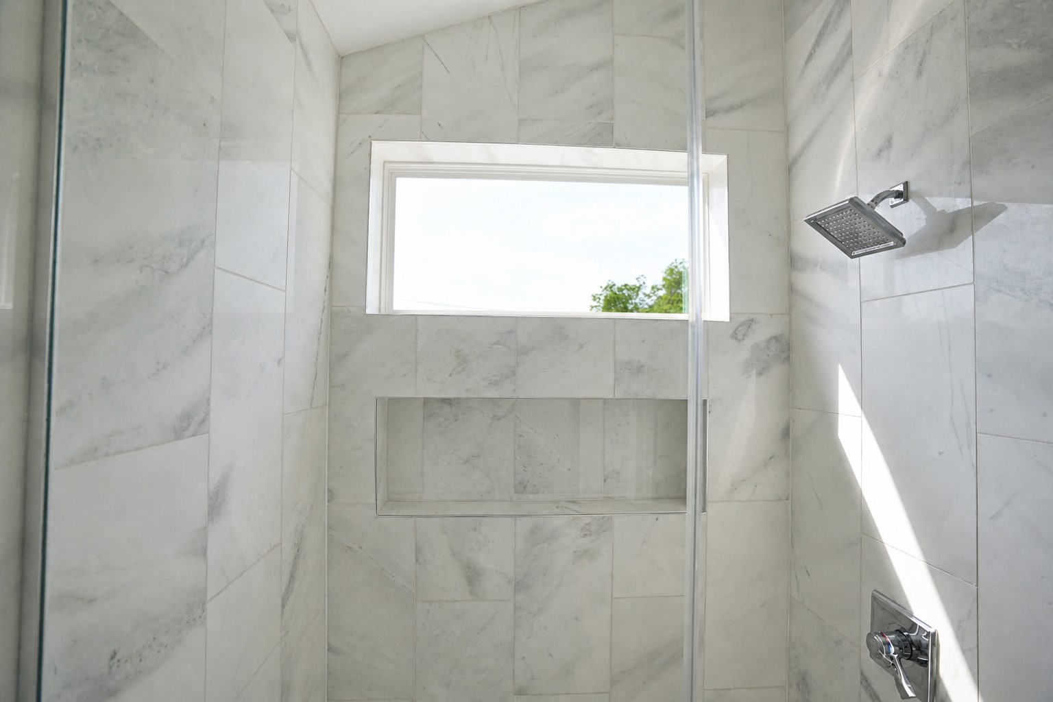 1123 Omega Avenue, Unit 1 Austin, TX 78721 - Photo 20 of 40 Shower enclosure featuring white marble-look tile, a recessed shower niche, and a rain showerhead
