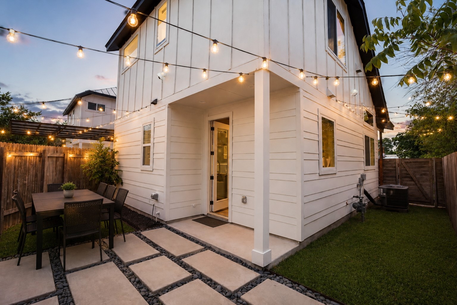 1123 Omega Avenue, Unit 1 Austin, TX 78721 - Photo 2 of 40 Private outdoor patio featuring large-format paver stones, pea gravel accents, and string lighting. Virtually Staged.