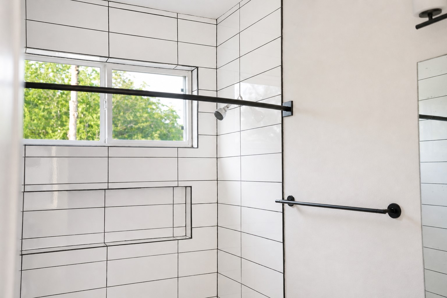 1123 Omega Avenue, Unit 1 Austin, TX 78721 - Photo 29 of 40 Bathroom featuring white rectangular tile with dark grout, a window, built-in shower niche, and matte black fixtures
