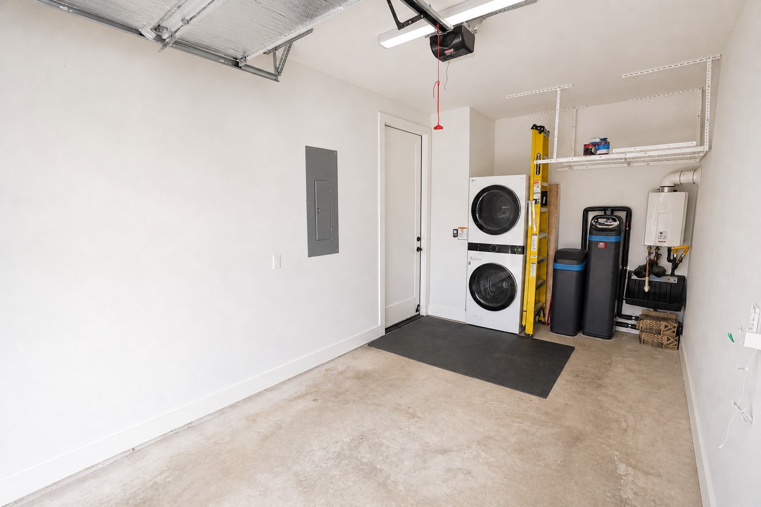 1123 Omega Avenue, Unit 1 Austin, TX 78721 - Photo 34 of 40 Garage interior featuring a stacked washer and dryer, an overhead storage rack, and a tankless water heater