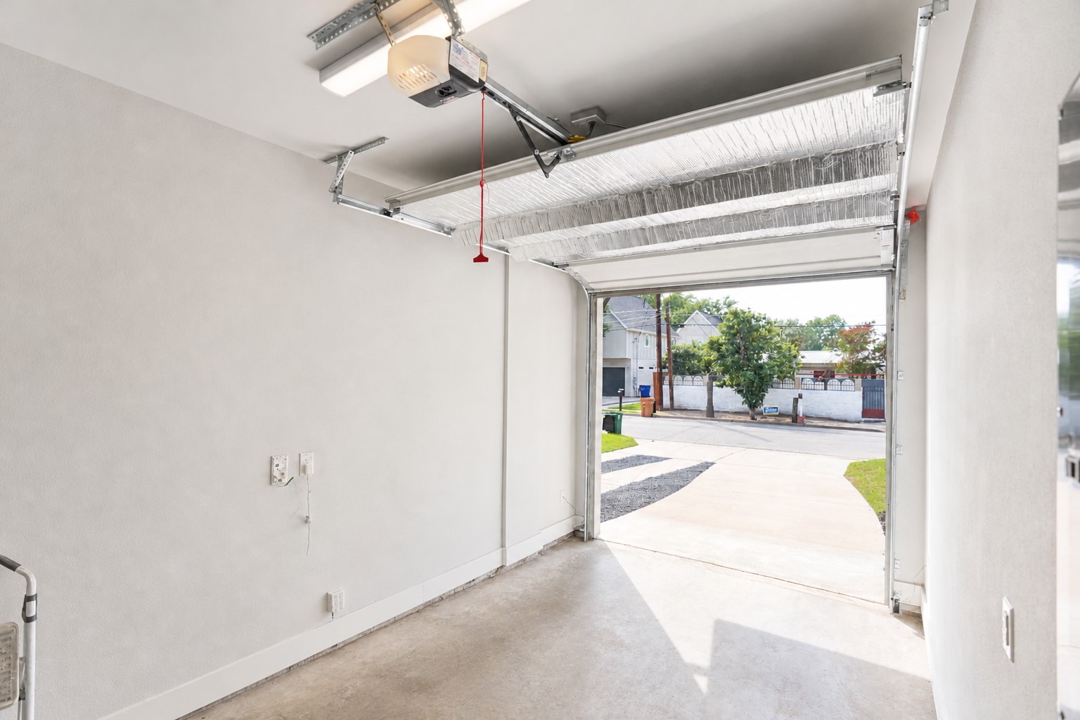 1123 Omega Avenue, Unit 1 Austin, TX 78721 - Photo 35 of 40 Garage interior featuring a concrete floor, white painted walls, and an insulated garage door with an automatic opener