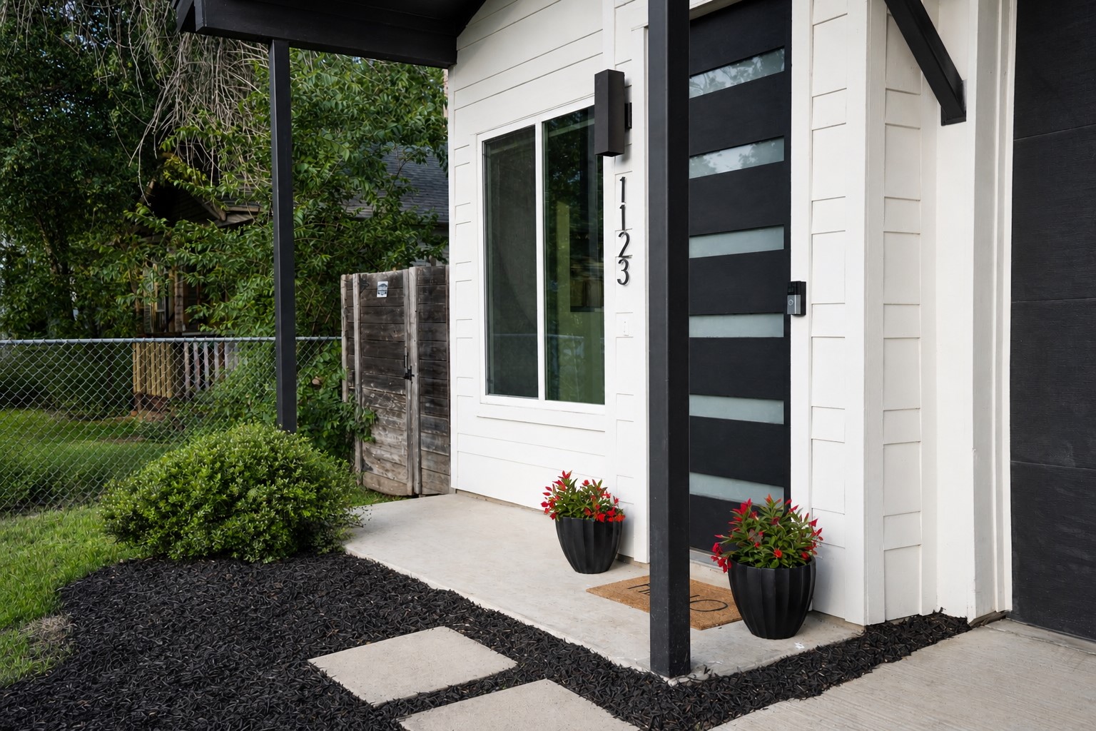 1123 Omega Avenue, Unit 1 Austin, TX 78721 - Photo 5 of 40 Modern entryway featuring a black door with frosted glass panels, white siding, and a concrete pathway