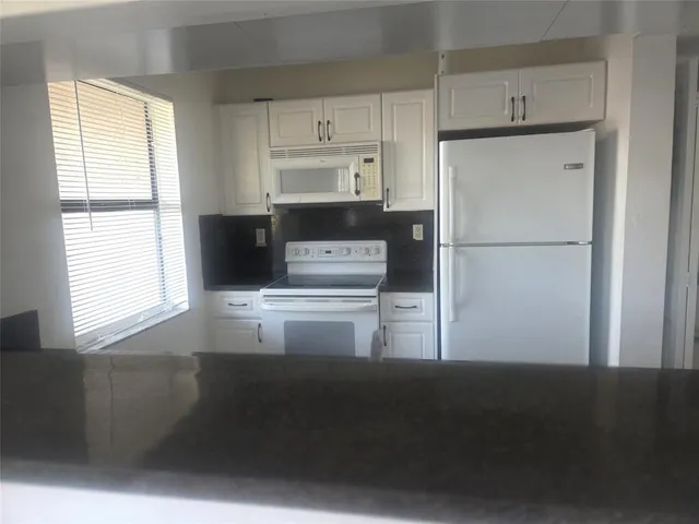 a kitchen with a refrigerator a stove a microwave and a window