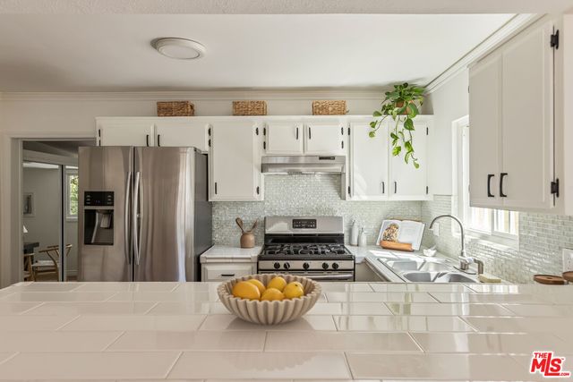 a kitchen with stainless steel appliances granite countertop a sink and a refrigerator