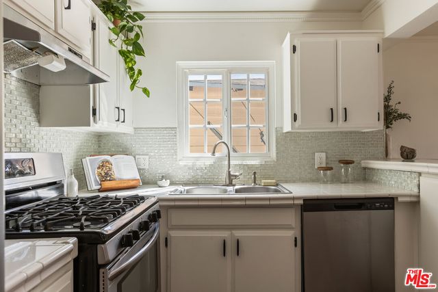a kitchen with granite countertop a sink stove and cabinets