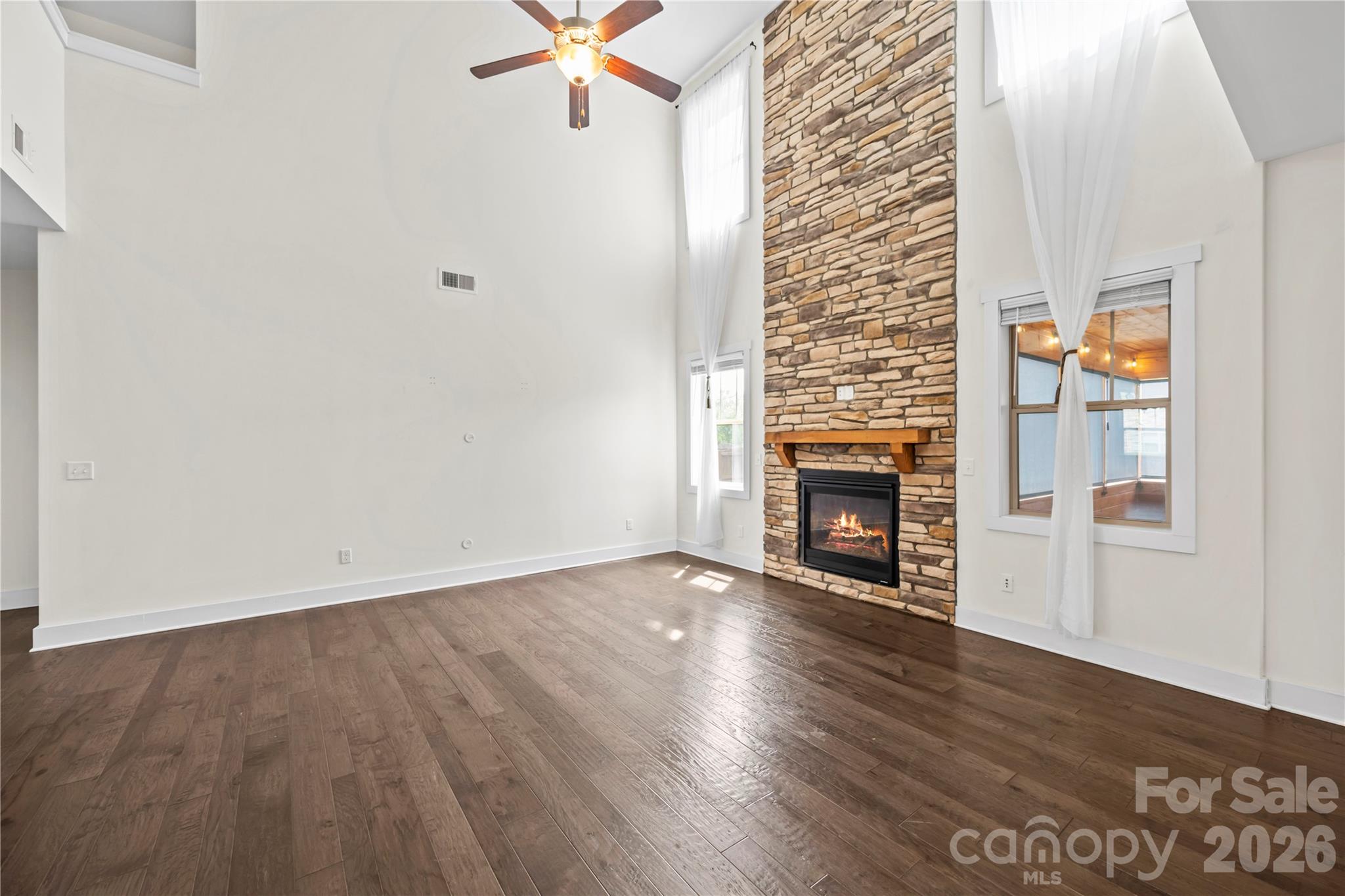 4 Henbit Way Arden, NC 28704 - Photo 4 of 38 an empty room with wooden floor a fireplace and windows