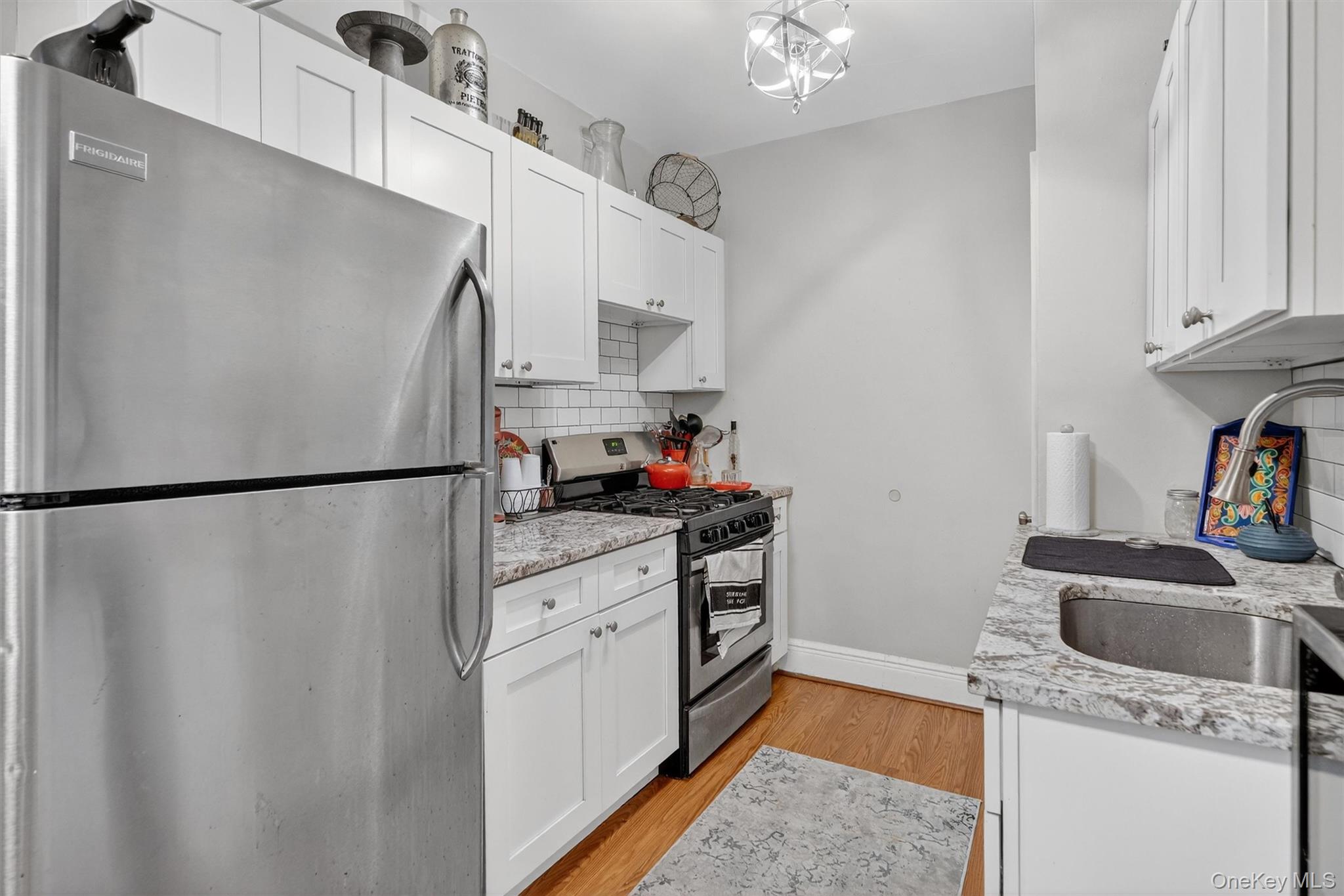 475 Bronx River Road, Unit 2D Yonkers, NY 10704 - Photo 13 of 27 Kitchen with stainless steel appliances, white cabinets, light wood finished floors, and light stone countertops