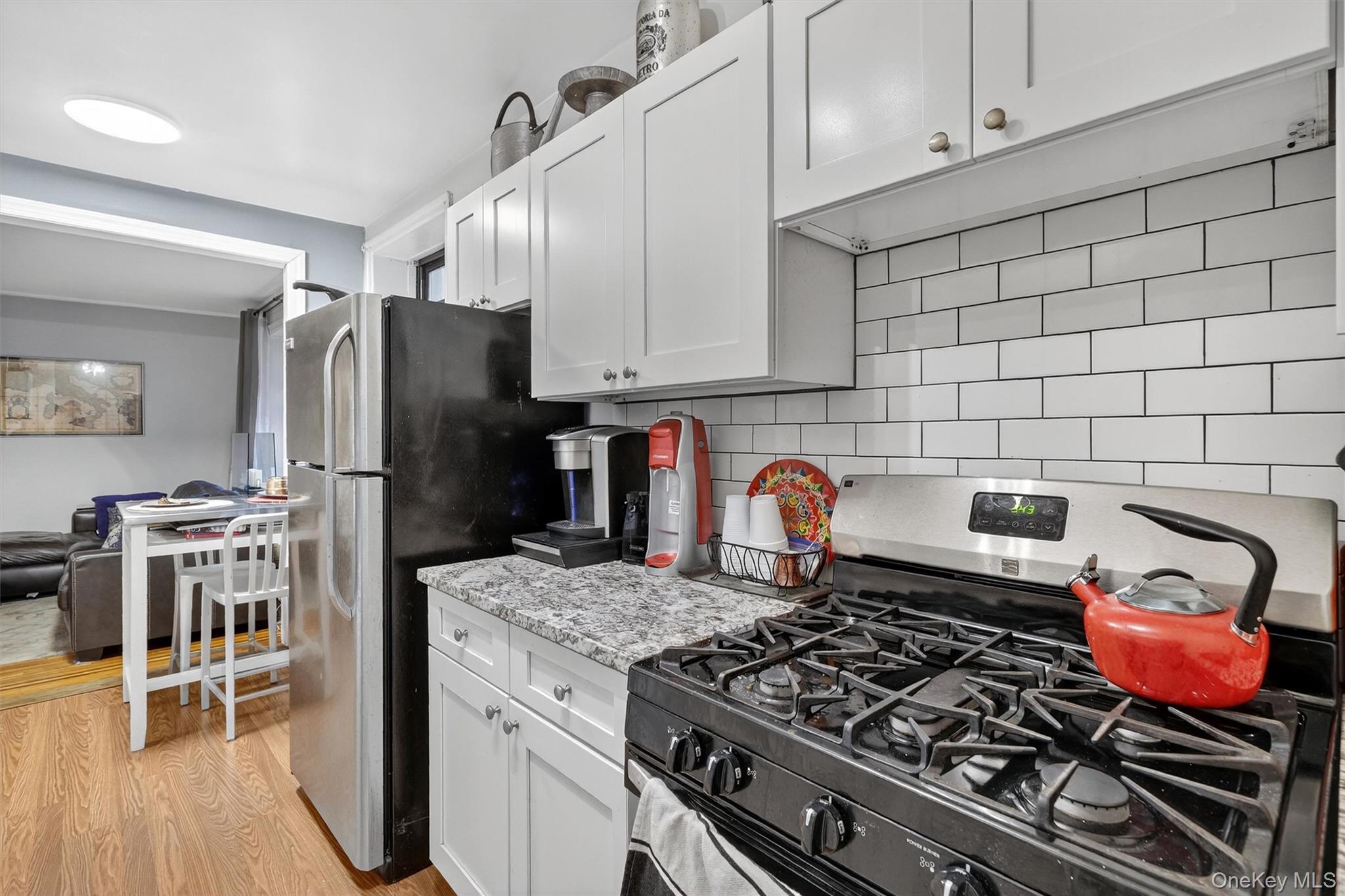 475 Bronx River Road, Unit 2D Yonkers, NY 10704 - Photo 16 of 27 Kitchen with appliances with stainless steel finishes, white cabinets, backsplash, and light wood-style floors
