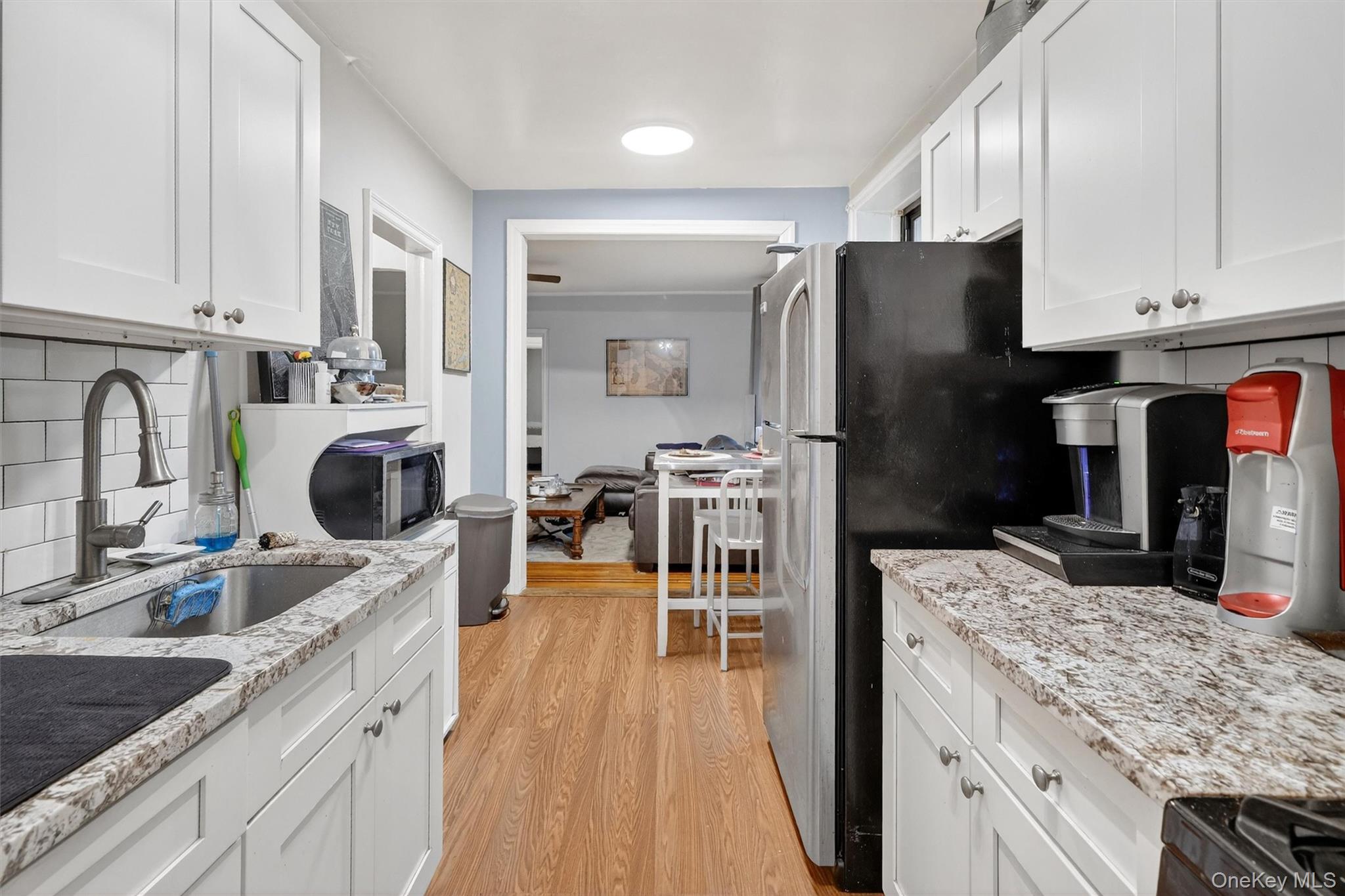 475 Bronx River Road, Unit 2D Yonkers, NY 10704 - Photo 18 of 27 Kitchen with decorative backsplash, white cabinets, light stone counters, and black appliances