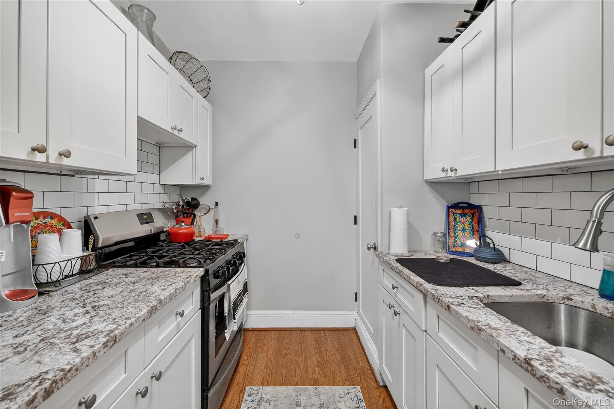 475 Bronx River Road, Unit 2D Yonkers, NY 10704 - Photo 19 of 27 Kitchen with stainless steel range with gas cooktop, white cabinets, light wood-type flooring, and light stone countertops