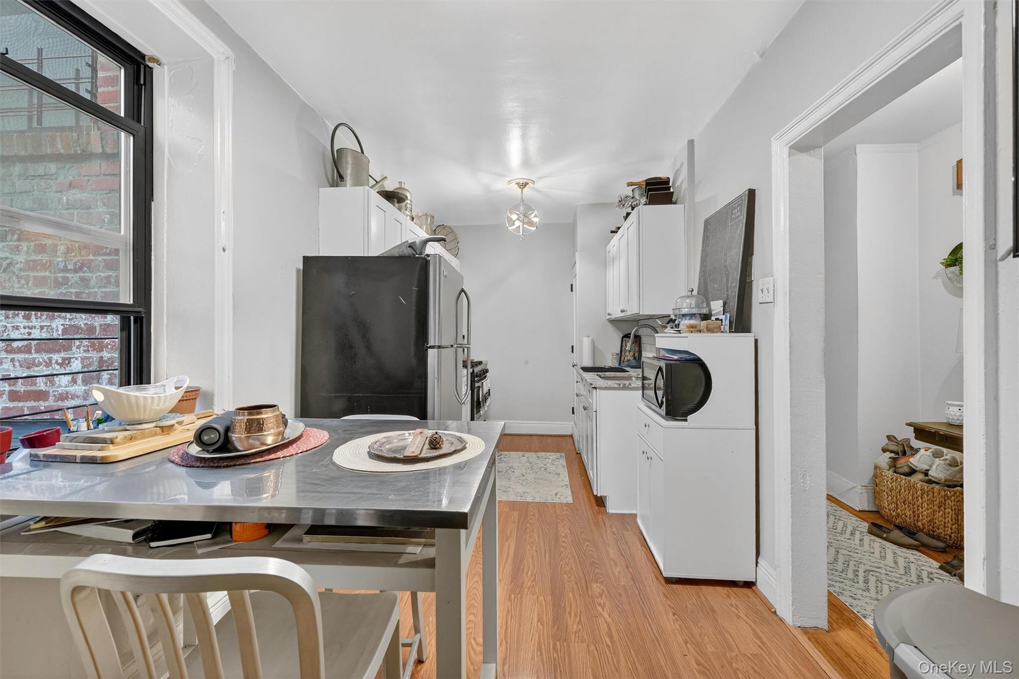 475 Bronx River Road, Unit 2D Yonkers, NY 10704 - Photo 20 of 27 Kitchen with white cabinetry, freestanding refrigerator, light wood-style floors, and black microwave