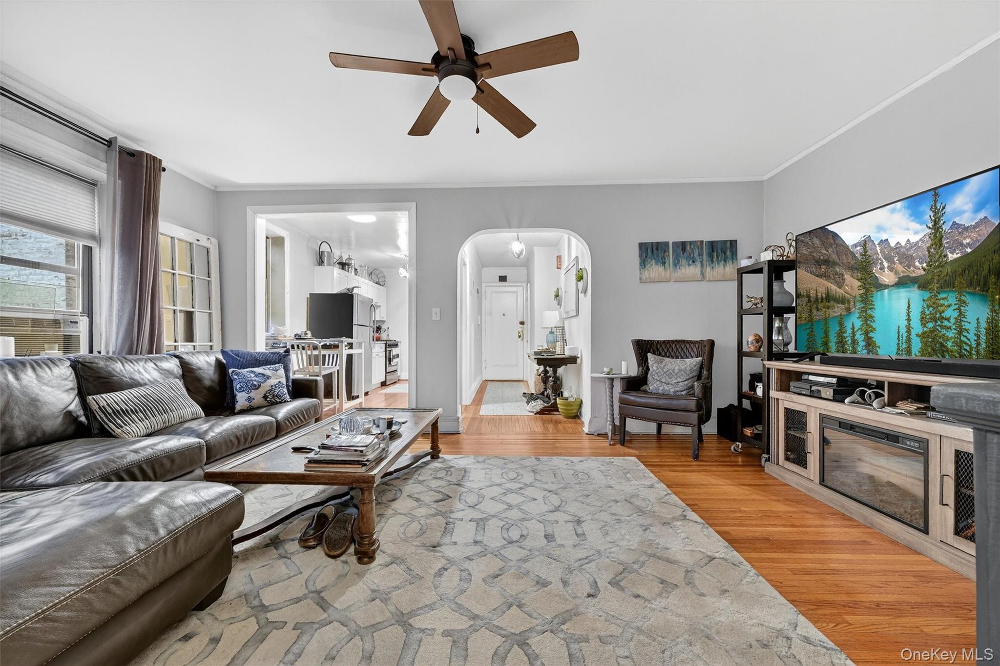 475 Bronx River Road, Unit 2D Yonkers, NY 10704 - Photo 10 of 27 Living area featuring arched walkways, light wood-style floors, a ceiling fan, ornamental molding, and cooling unit