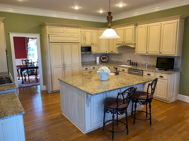 a kitchen with stainless steel appliances granite countertop a stove a refrigerator a sink a dining table and chairs with wooden floor