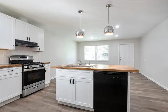 a kitchen with granite countertop a sink a stove and cabinets