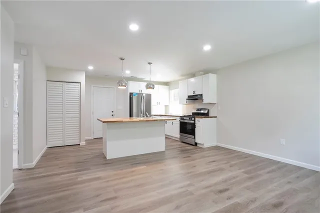 a large kitchen with stainless steel appliances kitchen island a large counter top and a stove top oven