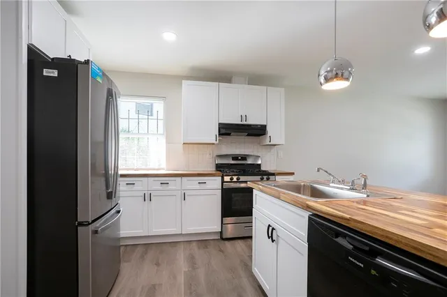 a kitchen with granite countertop stainless steel appliances a sink a stove a refrigerator and cabinets