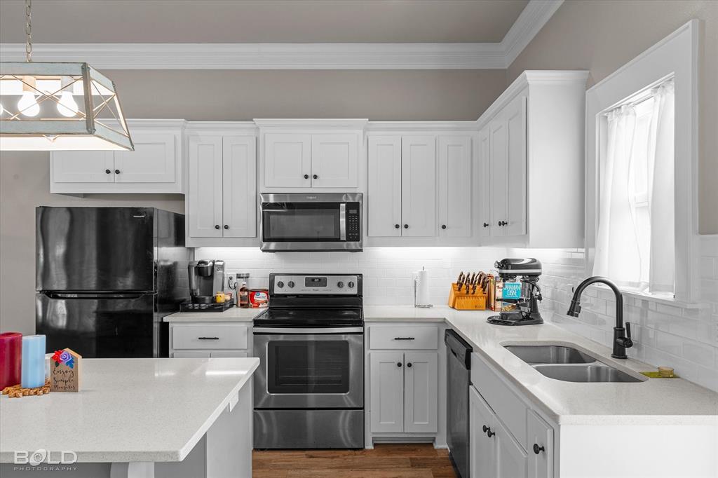 6896 Bethany Reed Circle Blanchard, LA 71107 - Photo 21 of 37 Modern kitchen featuring white shaker cabinetry, stainless steel appliances, white subway tile backsplash, light-colored countertops, and a double basin sink with a matte black faucet