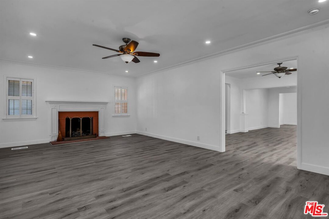 121 North Doheny Drive Beverly Hills, CA 90211 - Photo 3 of 20 a view of an empty room with wooden floor fireplace and a window