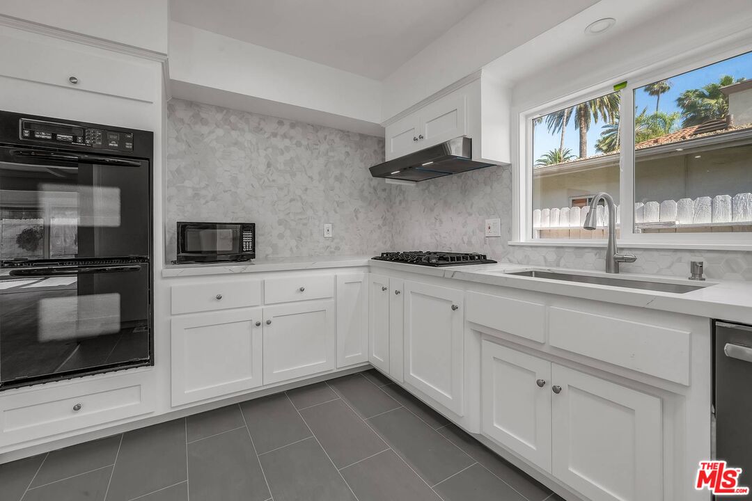 121 North Doheny Drive Beverly Hills, CA 90211 - Photo 7 of 20 a kitchen with stainless steel appliances a cabinets and a stove top oven