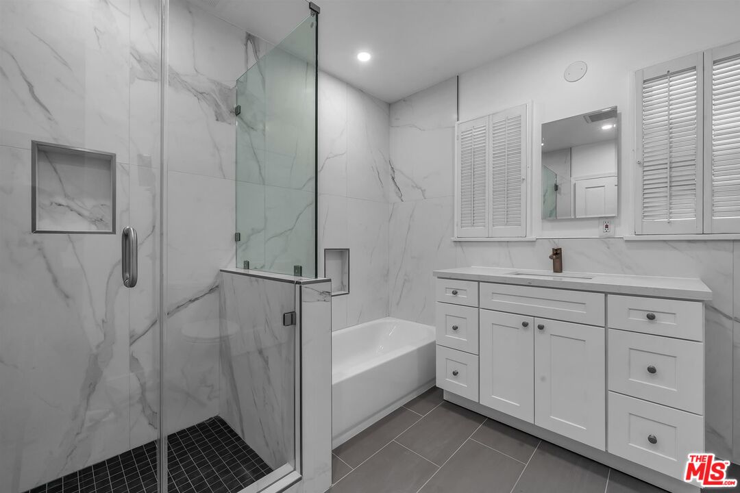 121 North Doheny Drive Beverly Hills, CA 90211 - Photo 10 of 20 a bathroom with a double vanity sink a mirror and a bathtub