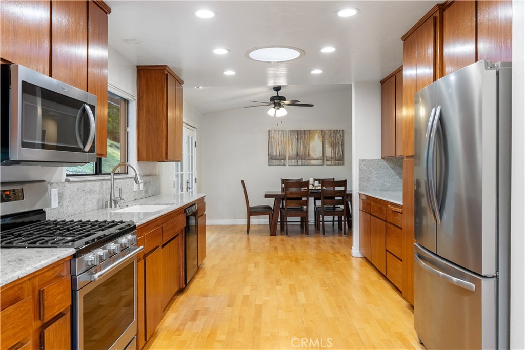 8505 Santa Cruz Road Atascadero, CA 93422 - Photo 18 of 59 a kitchen with stainless steel appliances granite countertop a refrigerator a stove a sink a dining table and chairs with wooden floor