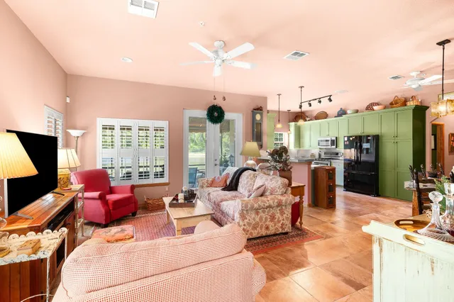 a living room with furniture a flat screen tv and a floor to ceiling window