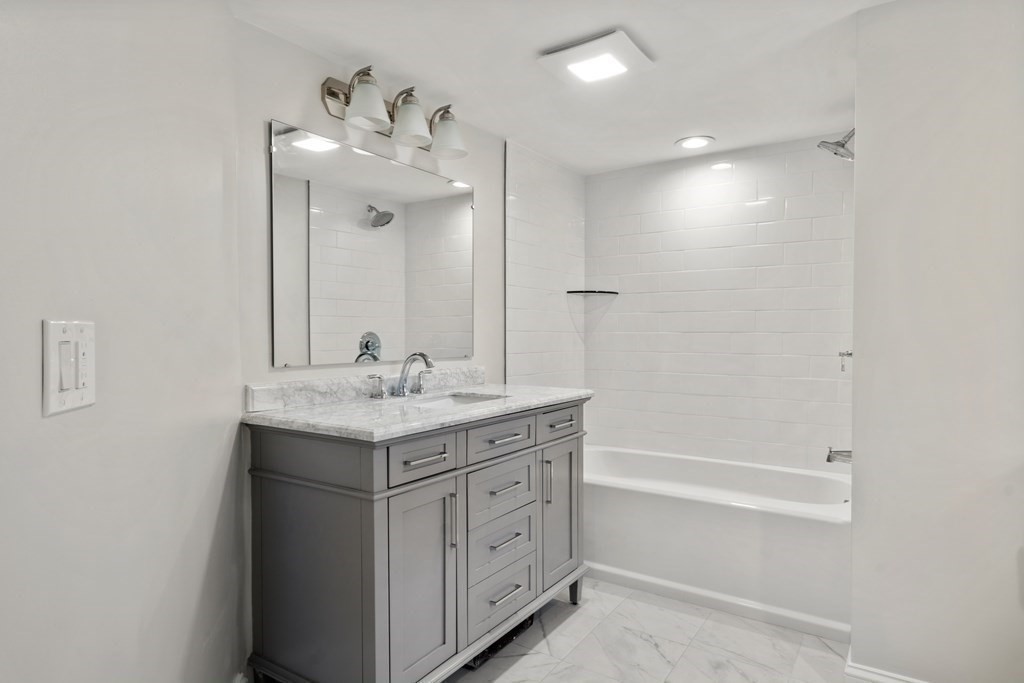 105 Plain Road Wayland, MA 01778 - Photo 22 of 25 a bathroom with a granite countertop sink a mirror and a bathtub
