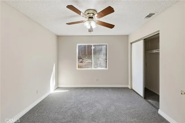 an empty room with windows and ceiling fan