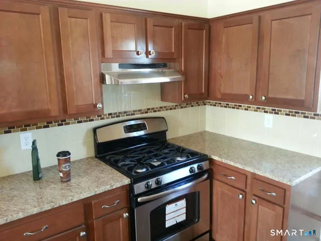 a kitchen with granite countertop a stove sink and cabinets