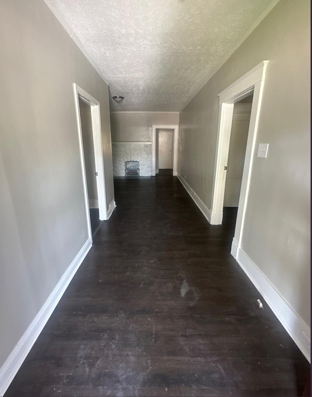 1165 Rayner Street Memphis, TN 38106 - Photo 16 of 16 Interior hallway featuring wood-finish flooring, light gray wall paint, white trim, and doors leading to other rooms