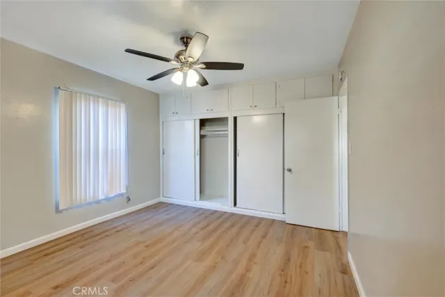 a view of empty room with wooden floor and fan