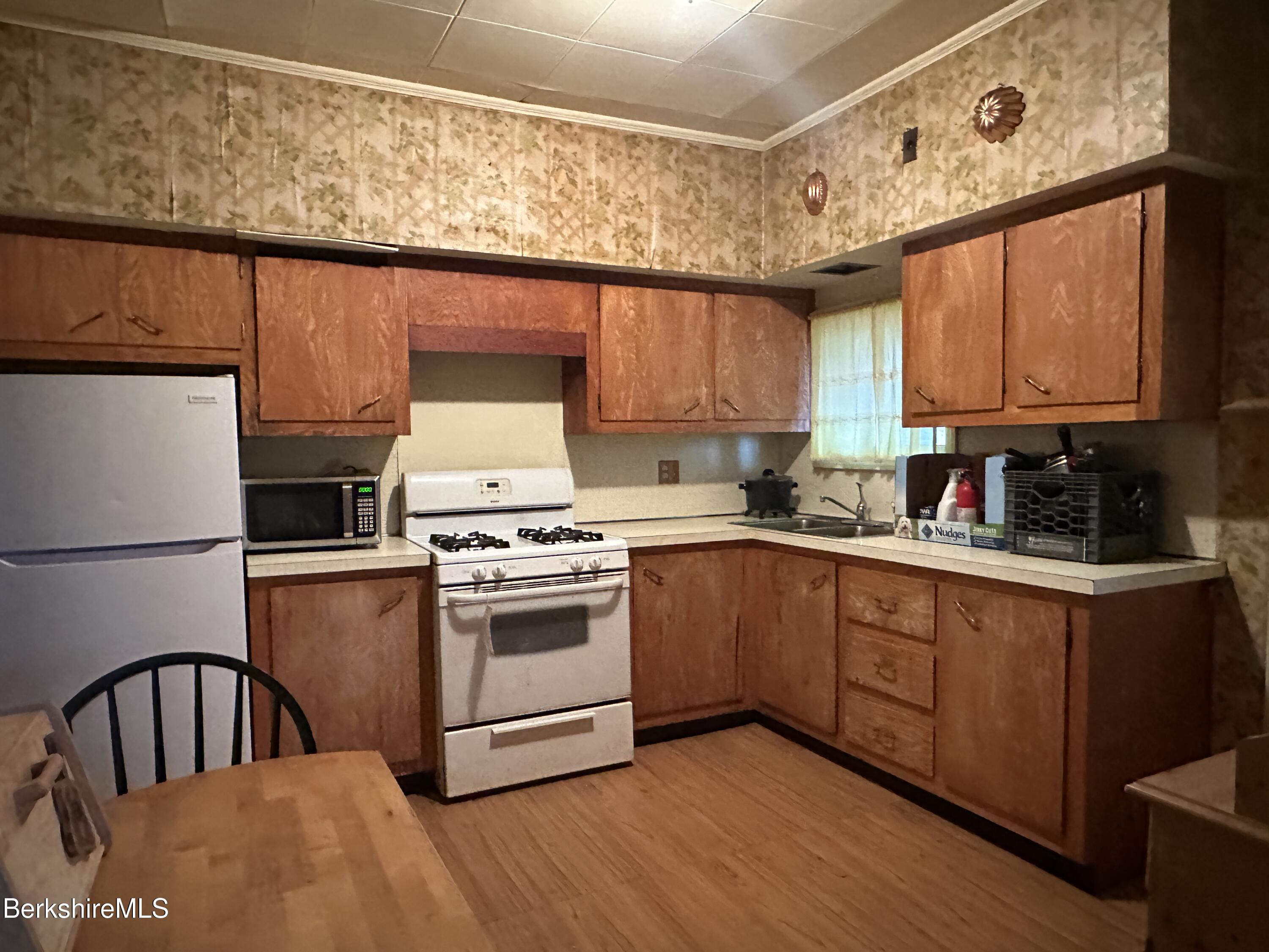 165-167 Appleton Avenue Pittsfield, MA 01201 - Photo 23 of 35 a kitchen with granite countertop a stove top oven a sink dishwasher and white cabinets with wooden floor
