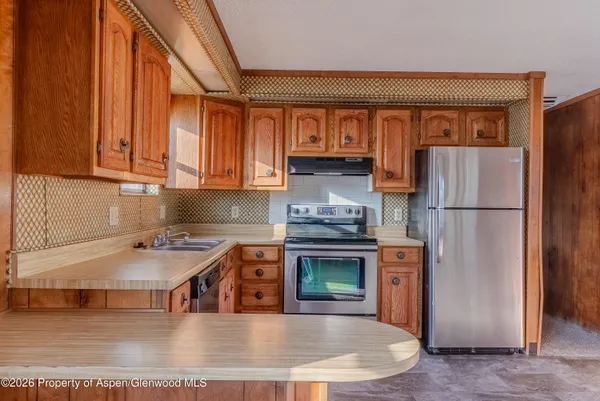 a kitchen with stainless steel appliances granite countertop a refrigerator a stove and a sink with large countertops