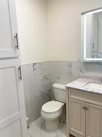 a bathroom with a granite countertop toilet and a sink