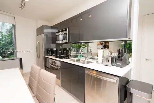 a living room with stainless steel appliances kitchen island granite countertop furniture and a rug