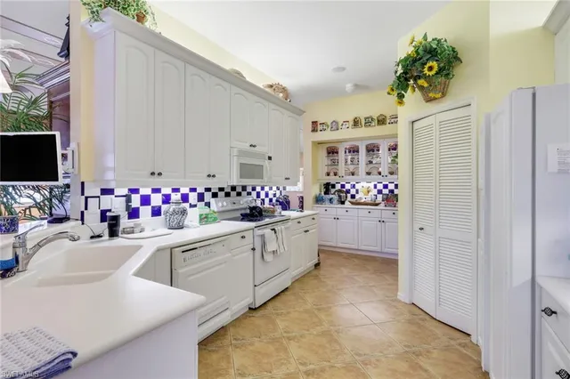 a kitchen with white cabinets and window