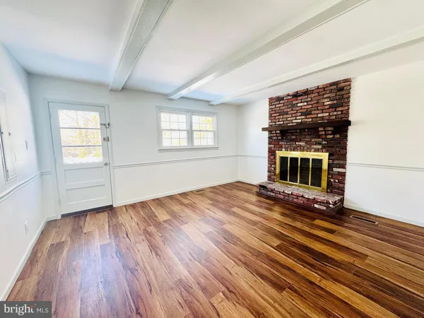 an empty room with wooden floor fireplace and windows