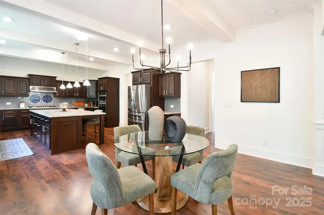 a kitchen with stainless steel appliances kitchen island granite countertop a dining table chairs and a refrigerator
