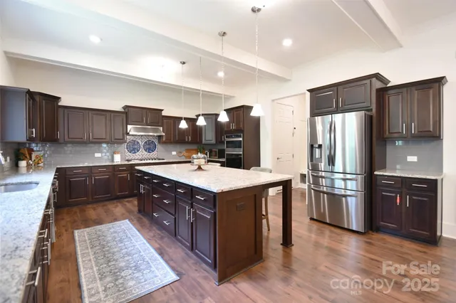 a kitchen with stainless steel appliances granite countertop a refrigerator a stove a sink and a oven