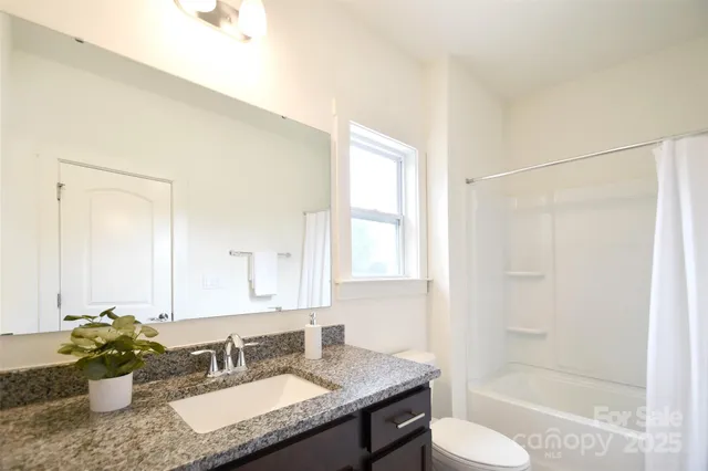 a bathroom with a granite countertop sink mirror toilet and bathtub