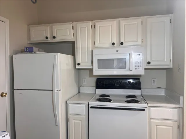 a kitchen with refrigerator a stove a microwave and cabinets