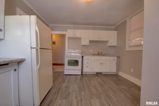 a view of a kitchen with a refrigerator and wooden floor