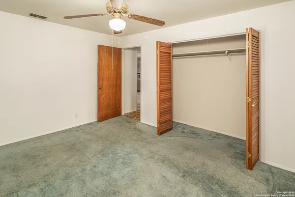 an empty room with a ceiling fan and closet