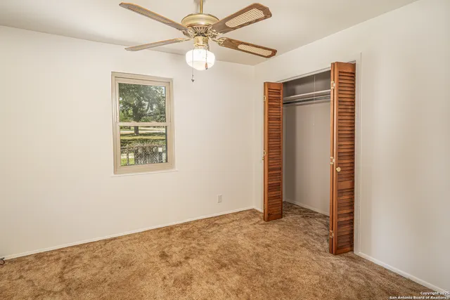 an empty room with windows and fan