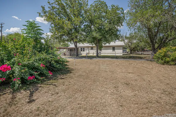 a front view of a house with a yard and tree s