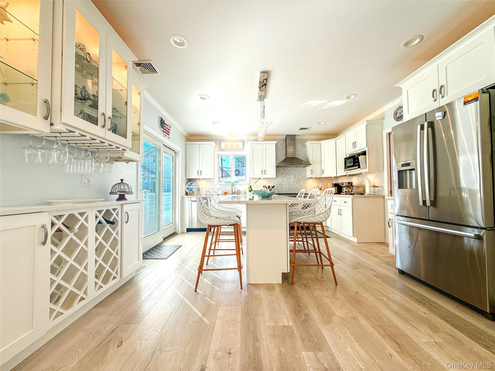97 Cedarhurst Avenue Point Lookout, NY 11569 - Photo 6 of 21 a kitchen with stainless steel appliances kitchen island granite countertop a refrigerator a stove a dining table and chairs with wooden floor