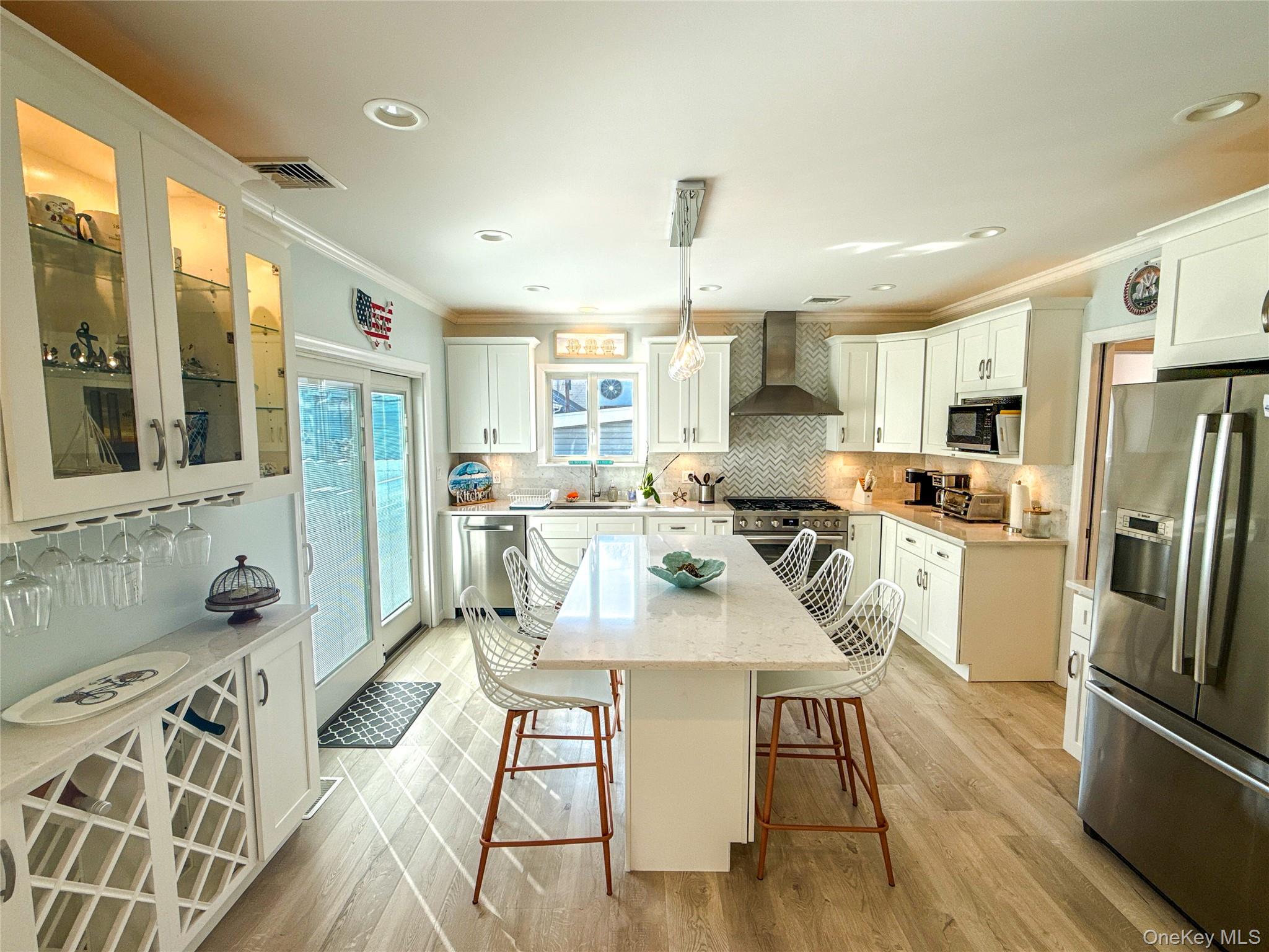 97 Cedarhurst Avenue Point Lookout, NY 11569 - Photo 7 of 21 a kitchen with stainless steel appliances a refrigerator a sink dishwasher a stove and white cabinets with wooden floor